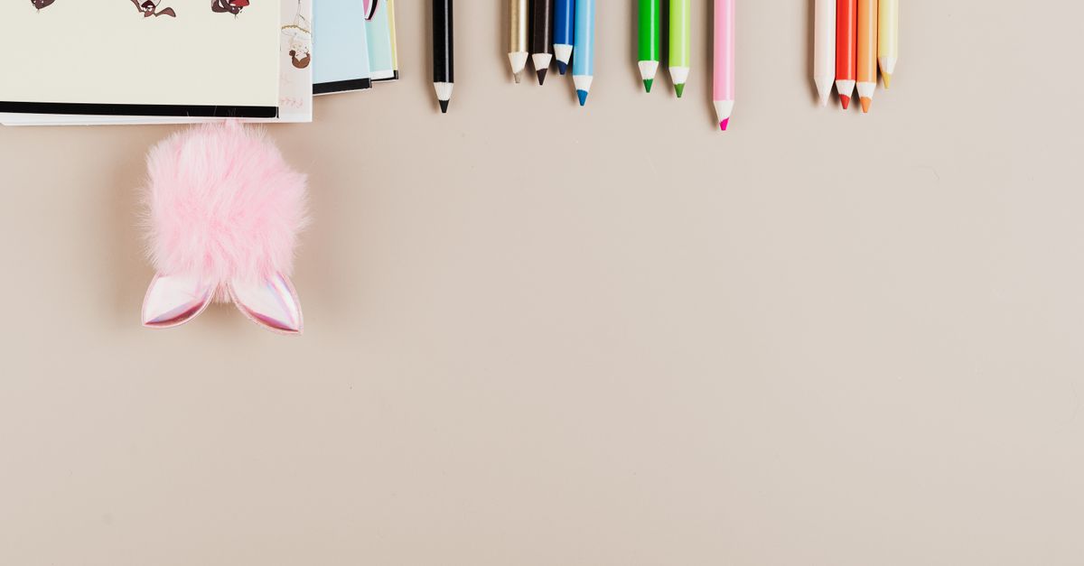 Mesa de trabajo con lápices de color, hojas impresas y pruebas de color sobre fondo claro